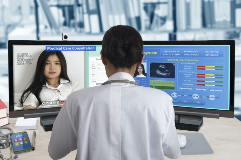 Female doctor working with two computers for distance patient consultation and searching her health information from medical record system